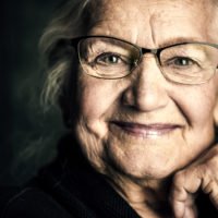 Portrait of a beautiful senior woman in elegant glasses smiling at camera.